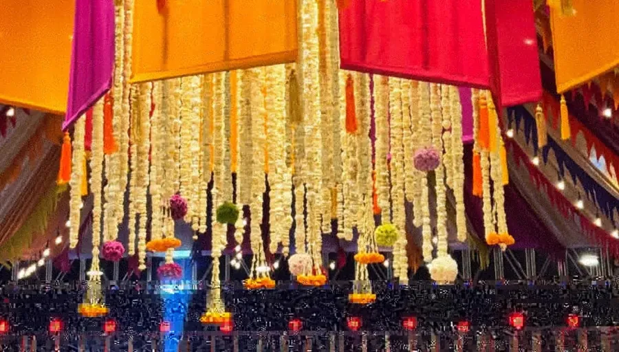 Hanging marigold strands and jewel-toned drapes lit from below