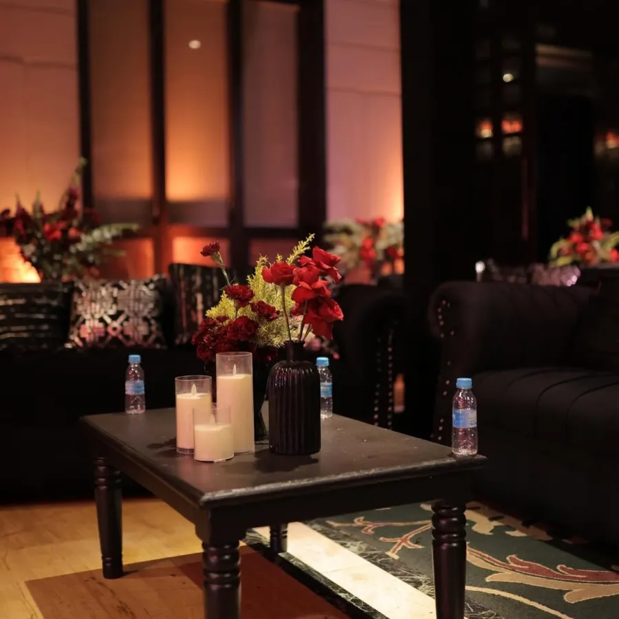 Warm indoor lounge with candles, florals and dark upholstered seating