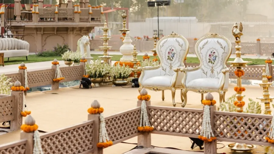 Marigold-lined aisle leading to ornate white ceremonial chairs