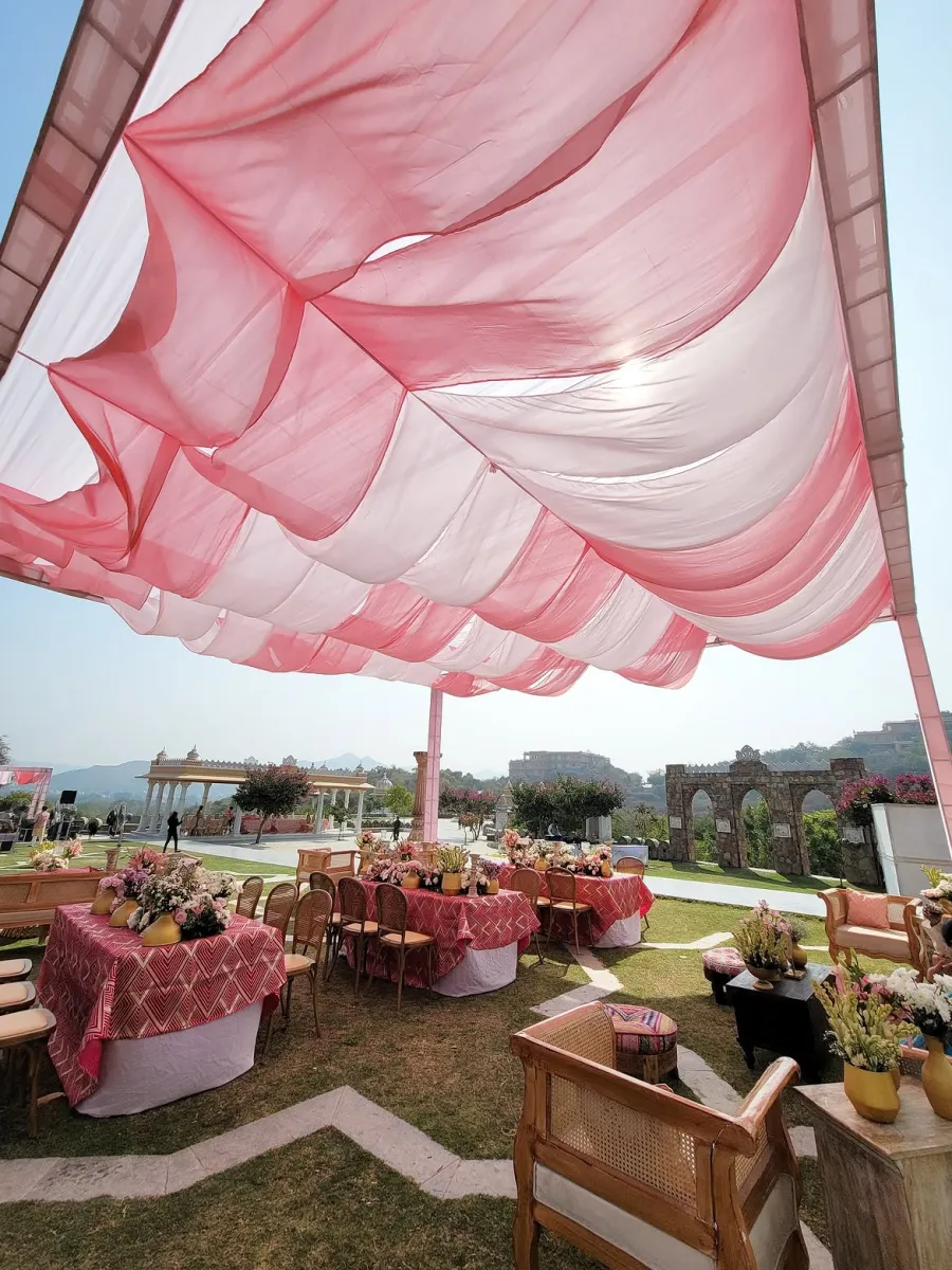 Blush and white draped canopy over garden tables, hills beyond