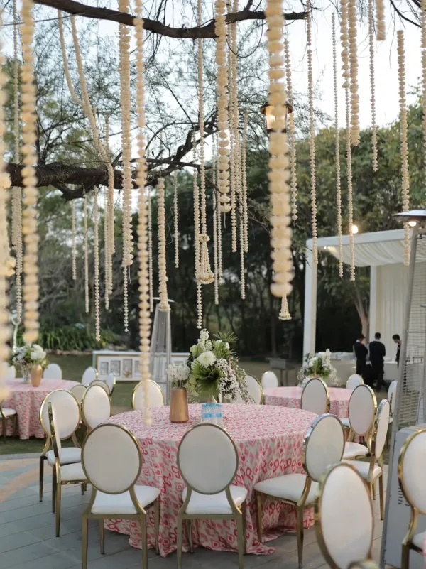 Floral strands hanging over round dining tables beneath the trees